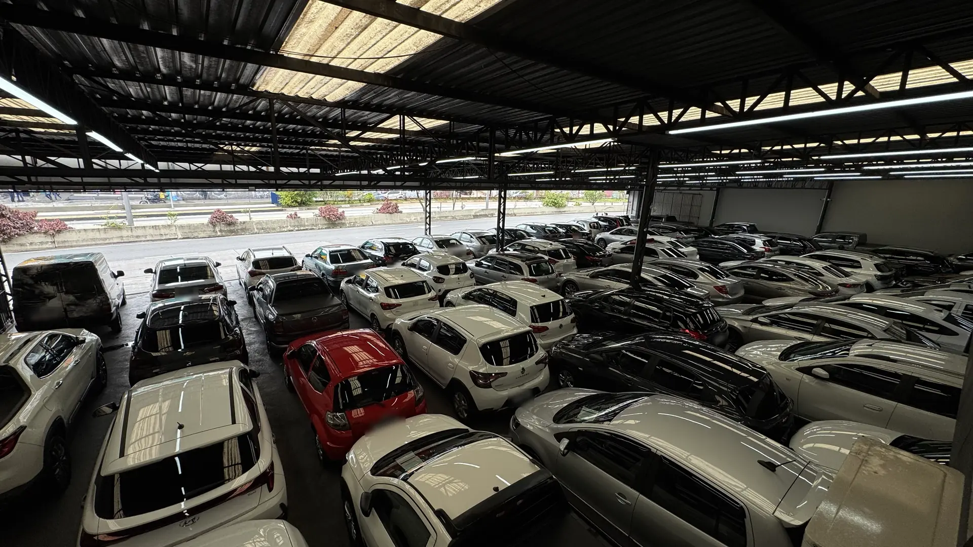 Pátio coberto da AutoNew visto do alto, com dezenas de carros de várias marcas